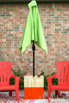 two red chairs and an umbrella in front of a brick wall