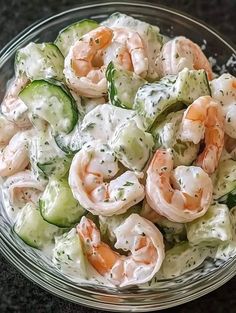 a bowl filled with shrimp and cucumber salad on top of a black table