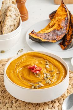 there is a bowl of soup on the table with bread and other food items around it