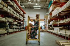 a woman sitting on a dolly in a warehouse