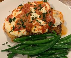 a plate with green beans and lasagna covered in marinara sauce on it