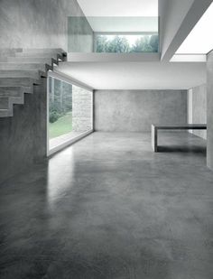 an empty room with concrete floors and stairs leading up to the second floor, in black and white