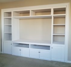 an empty living room with built in bookshelves and cupboards on the wall