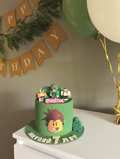 a birthday cake is on a table with balloons and streamers in front of it