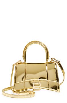 The curvilinear silhouette of this pint-sized satchel recalls the exaggerated shapes and proportions often used by master couturier Cristóbal Balenciaga. Polished B-shaped hardware that matches the golden calfskin reveres the brand's legacy while keeping with the current logomania craze. Magnetic-snap flap closure Top carry handle; removable, adjustable crossbody strap Exterior slip pocket Structured silhouette with flat base for stability Napa-lambskin lining Leather Made in Italy Designer Hand Gold Satchel With Metal Hardware For Office, Classic Gold Satchel With Metal Hardware, Formal Gold Satchel With Top Carry Handle, Modern Gold Satchel With Gold-tone Hardware, Gold Rectangular Shoulder Bag With Handle Drop, Chic Gold Satchel With Detachable Handle, Classic Gold Satchel For Evening, Designer Gold Satchel For Formal Occasions, Classic Gold Evening Satchel