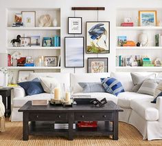 a living room filled with white furniture and lots of books on the shelves above it