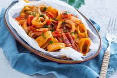 a plate filled with pasta and sauce on top of a blue cloth next to a fork