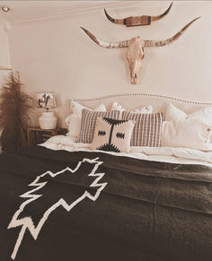 a black and white photo of a bed with an animal's head on the wall