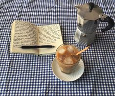 an open book sitting on top of a table next to a cup filled with ice