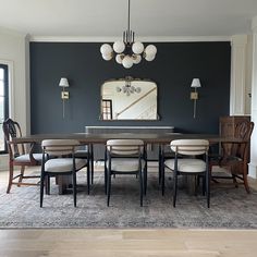 a dining room table and chairs in front of a large mirror with lights on it