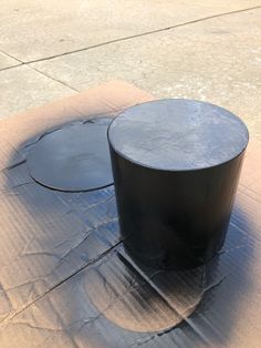 two black round tables sitting on top of a cement slab next to each other in front of a sidewalk