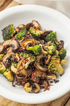 a white bowl filled with broccoli and mushrooms on top of a wooden table