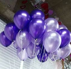 a bunch of purple balloons hanging from the ceiling