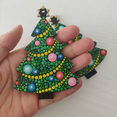 a hand holding a small christmas tree brooch