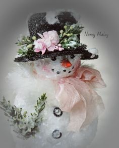 a snowman wearing a black hat with flowers on it