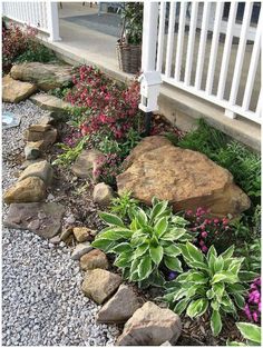 a garden with rocks and flowers next to a house