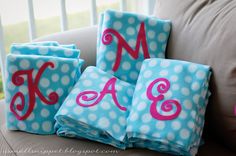 three blue and white polka dot towels with pink monogrammed letters on them sitting on a couch