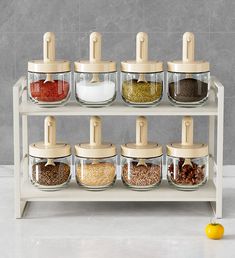 an assortment of spices and seasonings in glass containers on a shelf with wooden lids