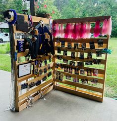 a wooden fence with pictures and other items hanging on the sides, in front of a grassy area