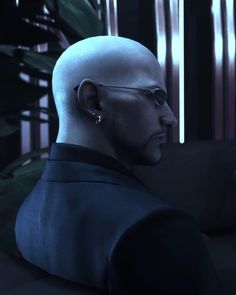 a man with glasses and a bald head in a dark room looking off into the distance