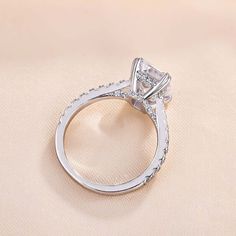 a close up view of a diamond ring on a white cloth with the center stone set in