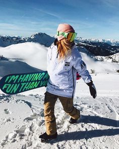 a snowboarder is walking in the snow with her board