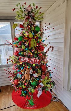 a decorated christmas tree in the corner of a room with a sign that says whovillee on it