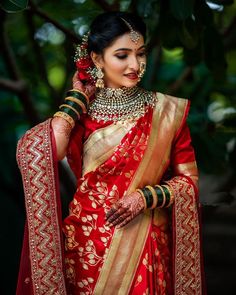 a woman in a red and gold sari is posing for the camera with her hands on her face