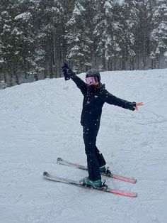 a person riding skis on a snowy surface with trees in the backgroud