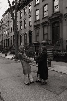 two women standing on the side of a street