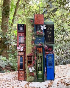 three books stacked on top of each other in front of some trees and bushes with flowers