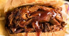 a pulled pork sandwich with bbq sauce on it and french fries in the background