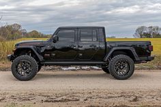 the black jeep is parked on the side of the road in front of some grass