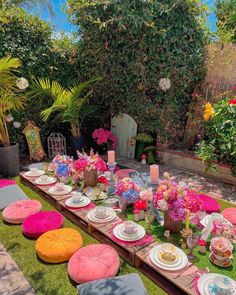 an outdoor table set up with plates and flowers