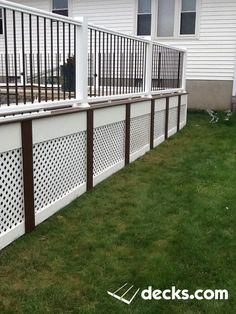 a dog is standing in the grass next to a white fence and some green grass