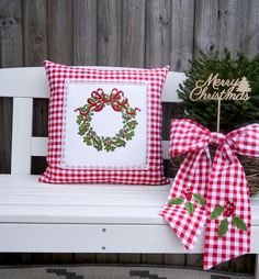 a white bench with a red and white checkered christmas pillow on top of it