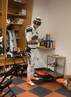 a football player is standing in the locker room with his helmet on and looking at his cell phone