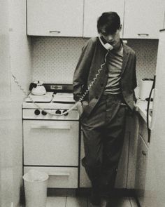 a man is standing in the kitchen talking on his phone