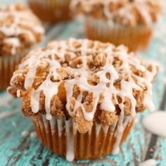 several muffins with icing on top of them sitting on a blue surface