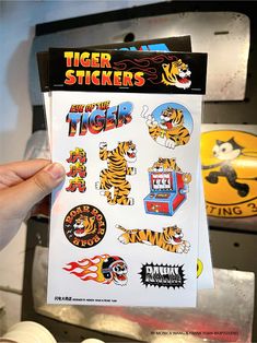 a person holding up a sticker sheet with tiger designs on it