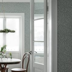 a dining room table and chairs in front of a window with potted plants on it