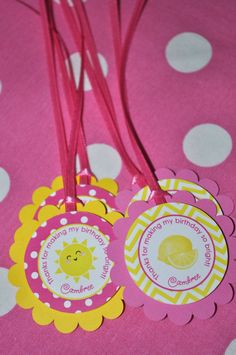 pink and yellow birthday tags with white polka dots on a pink tablecloth, one has a sun