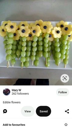 grapes are arranged on sticks with yellow flowers in the middle and black dots around them