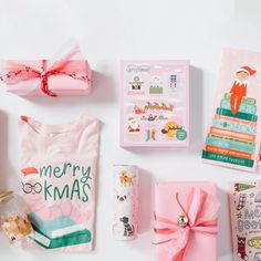 the contents of a christmas gift box laid out on a white surface with pink wrapping paper