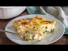 a piece of quiche on a plate with a fork and bowl in the background