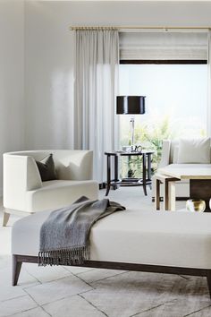 a living room with white furniture and curtains