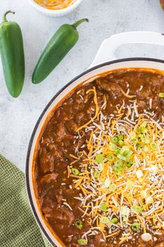 chili concoction with cheese and green peppers on the side