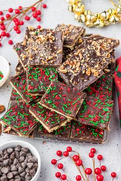 chocolate barkies with sprinkles and nuts on a tray next to christmas decorations