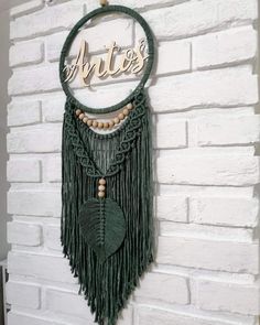 a white brick wall with a green macrame necklace hanging from it's side