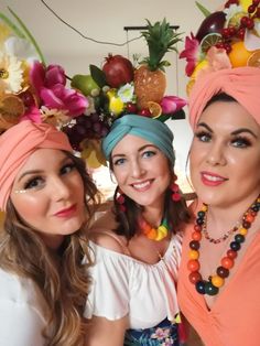 two beautiful women standing next to each other in front of flowers and fruit on the wall